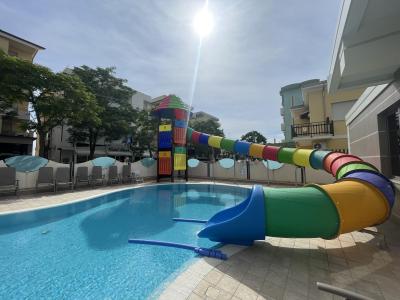 Piscina con scivolo colorato e lettini, situata all'aperto.