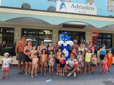 Gruppo di persone davanti a un hotel con mascotte blu.