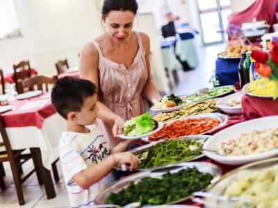 Mère et fils choisissent des plats colorés au buffet, ambiance chaleureuse et accueillante.