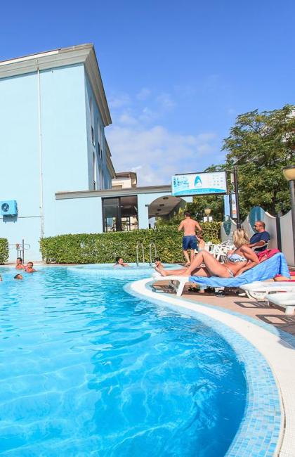 Piscina all'aperto con persone che si rilassano sotto il sole.