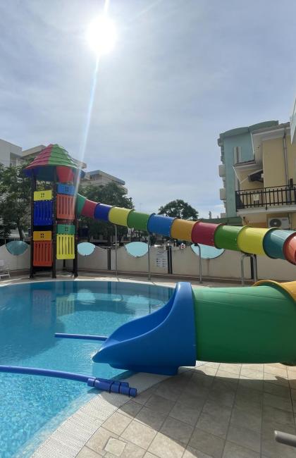 Piscina con scivolo colorato e lettini, situata all'aperto.