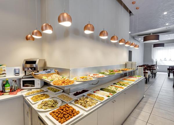 Buffet con piatti vari in un ristorante luminoso e moderno.