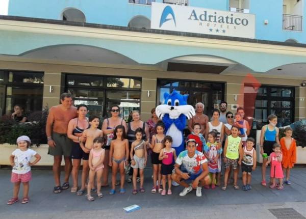 Gruppo di persone davanti a un hotel con mascotte blu.