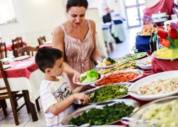 Mère et fils choisissent des plats colorés au buffet, ambiance chaleureuse et accueillante.